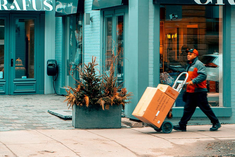 An image of a man moving shipping boxes down a sidewalk