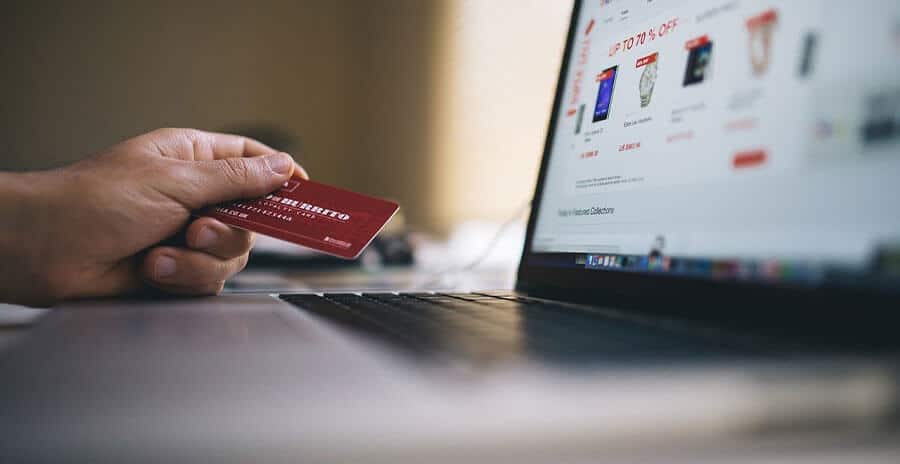 A person holding a credit card while looking on online shopping sales on a laptop