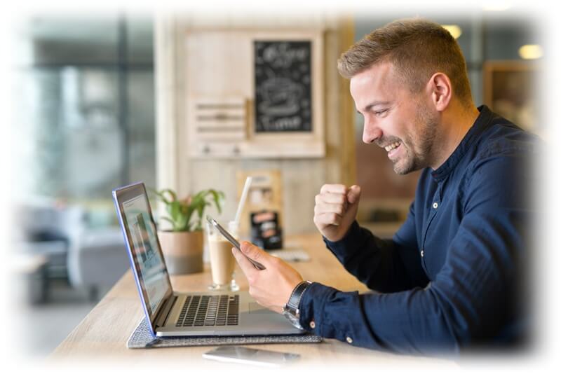 happy businessman looking at phone and laptop