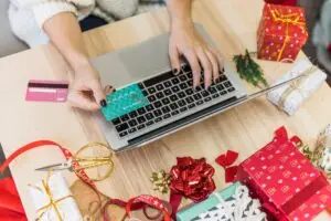woman using laptop with credit card, holiday decor around