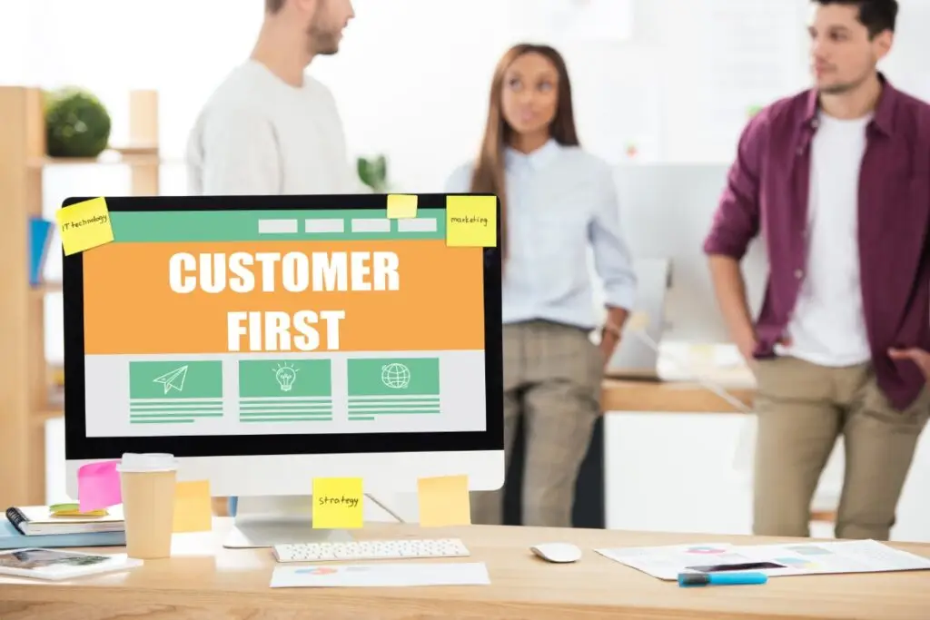 computer screen showing "Customer First" with workers in the background