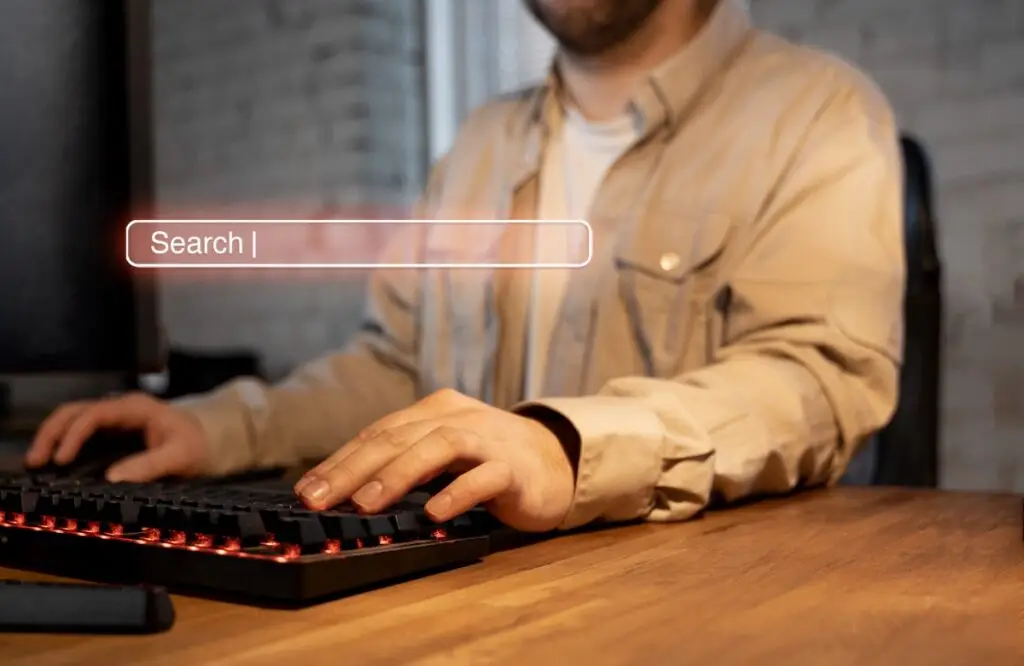 man using computer keyboard with search bar showing in front of him