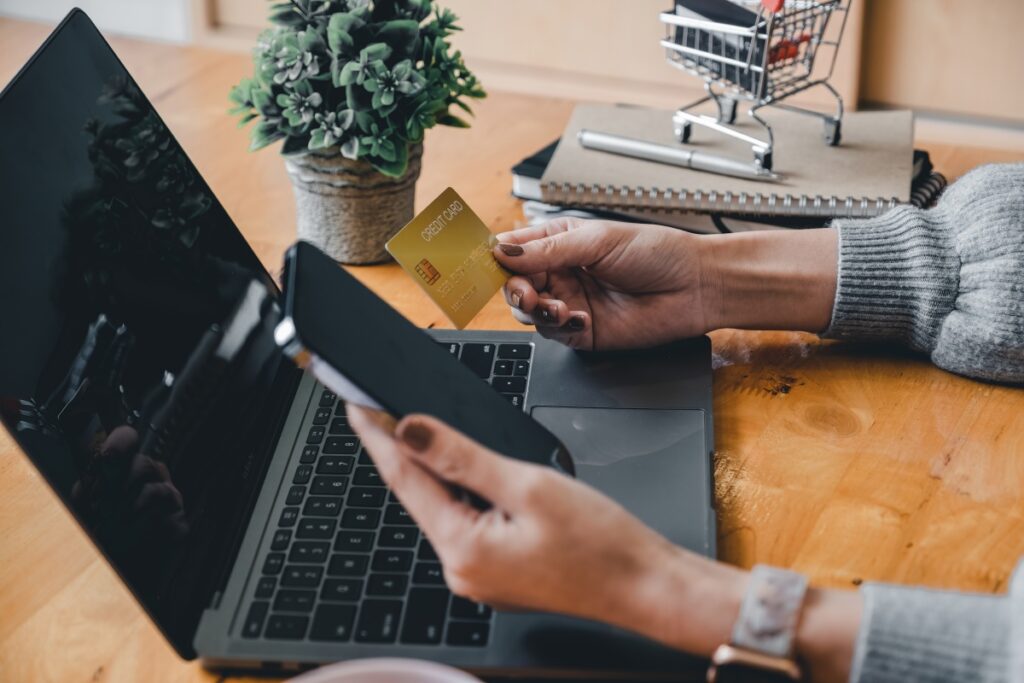 close up of a woman holding a credit card and phone in front of a computer
