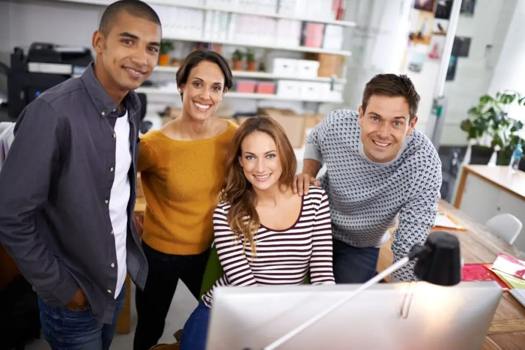 happy working team smiling around computer