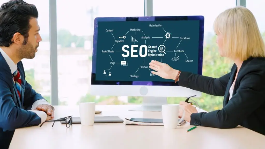 man and woman employees looking at computer screen showing SEO strategy