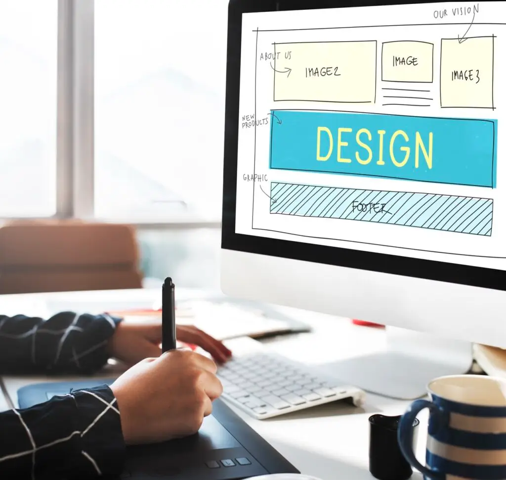 close up of designer using computer with screen showing a web design layout