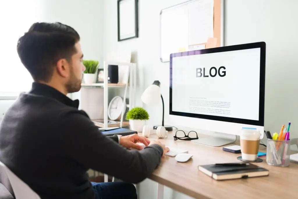 man working at a computer with a blog screen